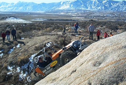 1986 Ford Bronco - A modified off-road vehicle navigates a challenging rocky incline with spectators observing the action.