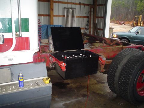 1966 International School Bus - A truck chassis is shown with an open battery box and a large tire, with another vehicle visible in the background.