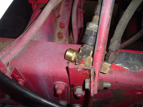 1966 International School Bus - Hydraulic fittings are visible on the red chassis of a vehicle.