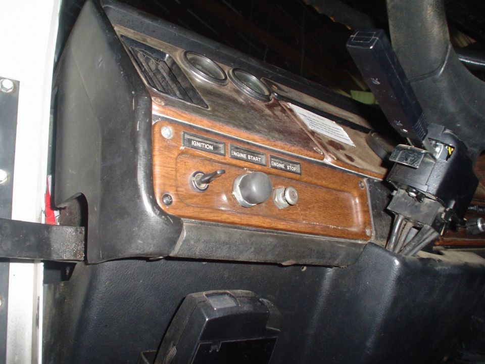 Dashboard interior showing ignition, engine start, and engine stop switches with wood grain trim