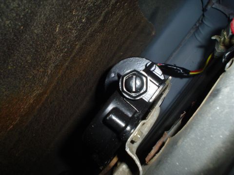 1984 Ford Bronco - Close-up of a vehicle's interior seatbelt buckle mechanism, with visible wiring and signs of rust.