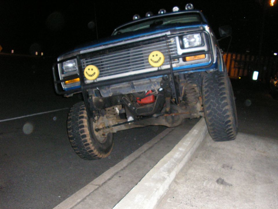 Blue pickup truck with smiley face lights on a curb