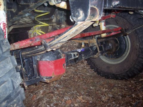 1995 Toyota Tacoma - Close-up view of the rear axle and suspension system of a truck, showing leaf springs and red shock absorbers.