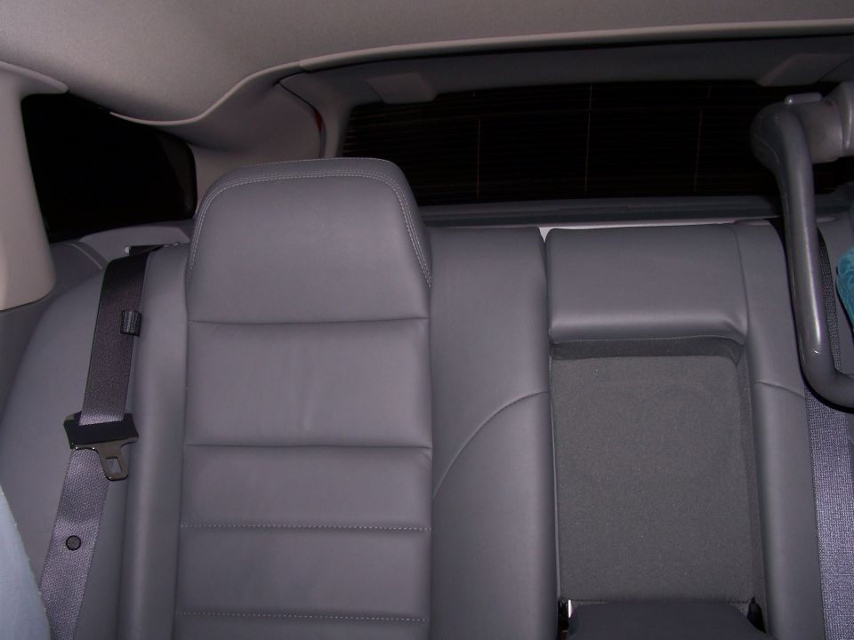 Rear seats of a car with gray leather upholstery and a seatbelt