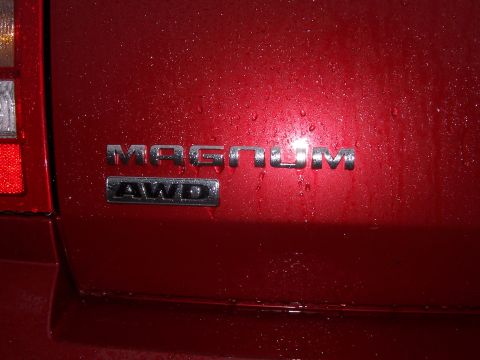 1979 Ford F-150 - Close-up of the 'Magnum AWD' emblem on the rear of a red vehicle, with water droplets visible on the paint.