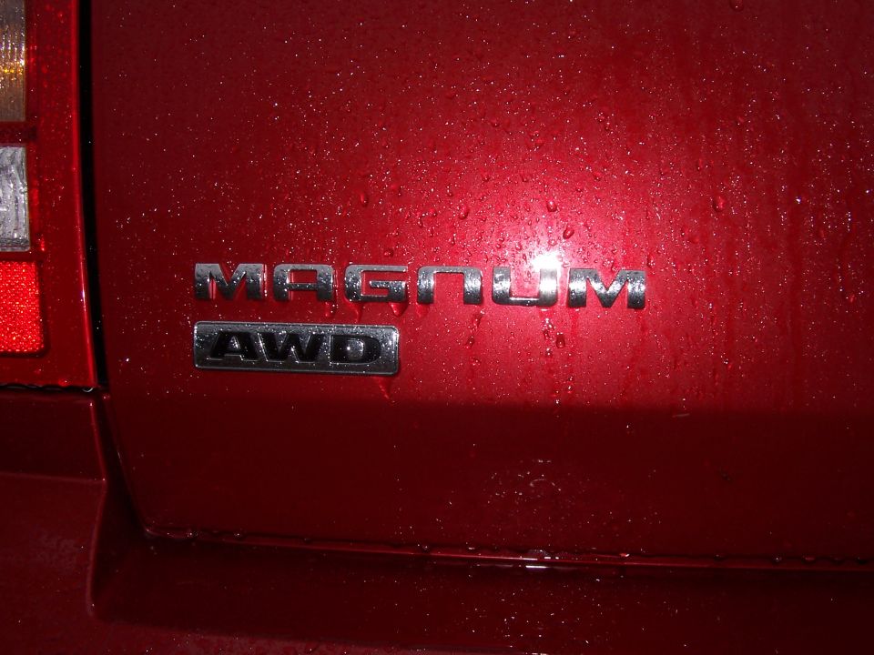 Rear of red vehicle showing Magnum and AWD badges. Water droplets on surface