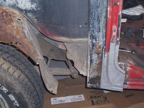 1978 Ford Bronco - Close-up of a vehicle's rusty quarter panel and tire, showing repair work on the door jamb.