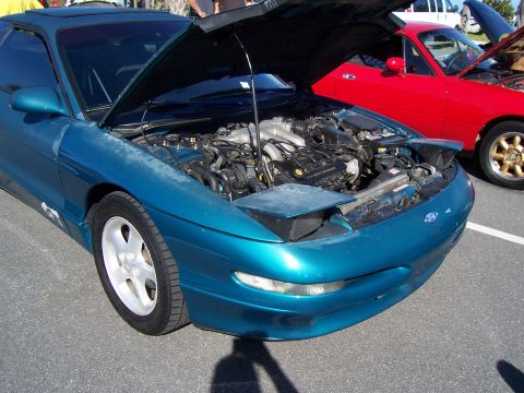 1994 Ford Probe - A teal Ford Probe is parked with its hood open, revealing the engine, next to a red Mazda Miata.