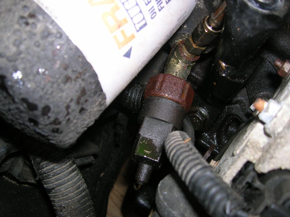 Close-up of an oil pressure sensor and oil filter on an engine