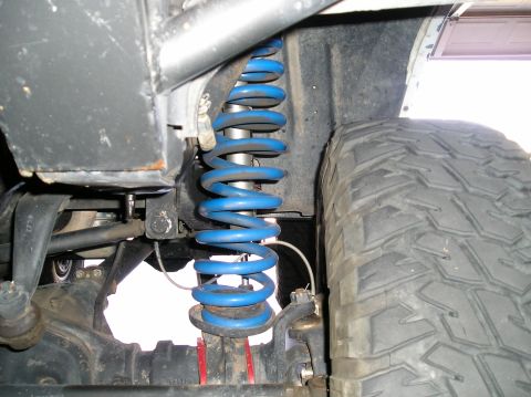 1993 Ford Bronco - Close-up view of a vehicle's suspension system, highlighting a blue coilover shock and a large tire.
