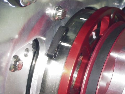 1990 Ford Mustang - Detail of an engine's pulley system, showing machined metal and red anodized parts.