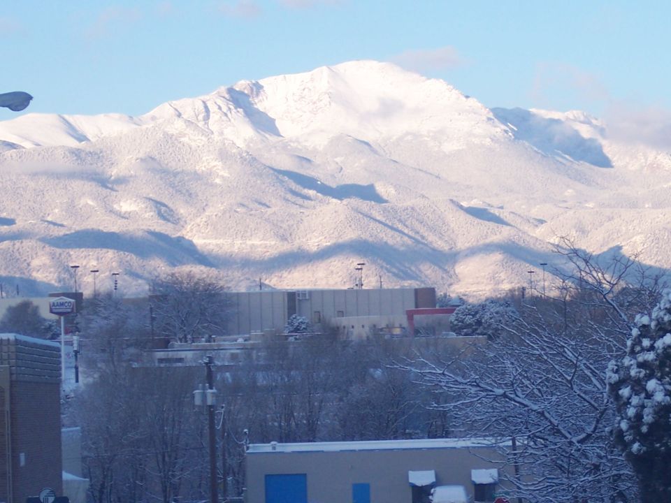 snowy mountains loom over buildings and trees