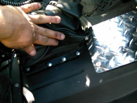 1986 Ford Bronco - Close-up of a T-case shifter boot and diamond plate trim inside a vehicle's interior.