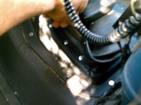 1986 Ford Bronco - Hand reaching for a black corrugated cable with a metal end.