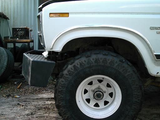 White 1986 Ford Bronco front fender, bumper, and large tire