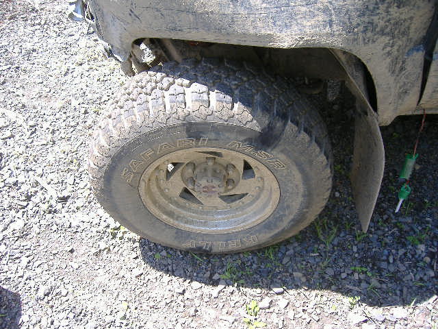 Side view of a dirty truck's wheel and fender with "Safari MSR" tire