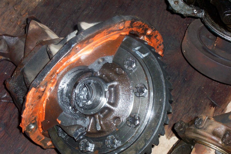 Differential carrier and ring gear with orange sealant on a wooden bench