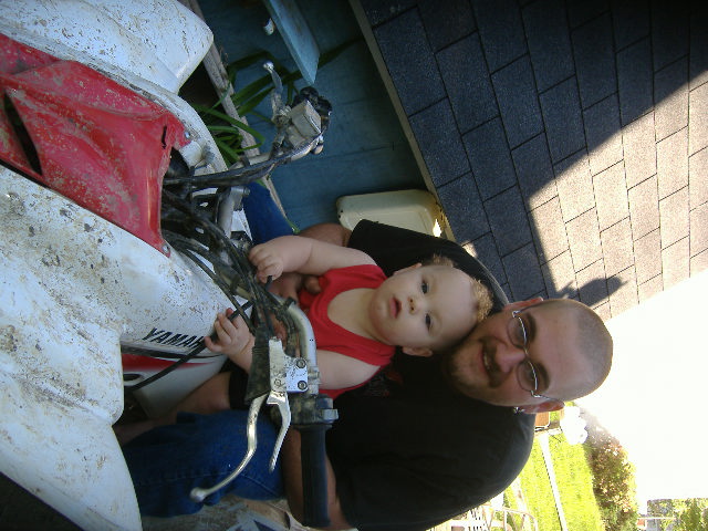 Man and baby on a white and red Yamaha ATV outdoors