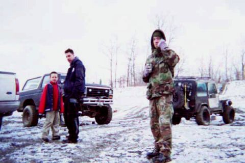 1986 Ford Bronco - A snowy scene features a lifted Ford Bronco and a Jeep Wrangler, with two individuals standing nearby.