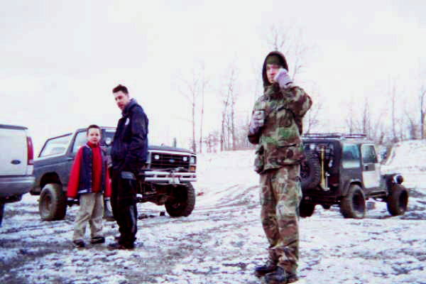 Two people stand by a lifted Ford Bronco, with a Jeep Wrangler in the background