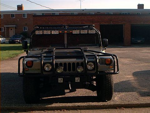 1986 Ford Bronco - A gray Hummer H1 is parked in front of a brick building with garages.