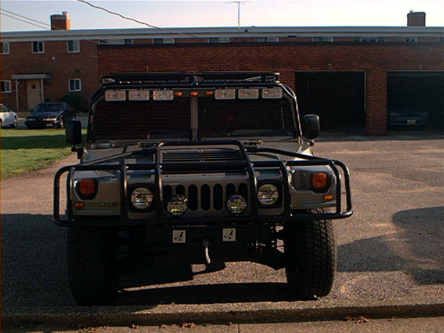 Gray Hummer H1 with a roof rack, brush guard, and multiple lights