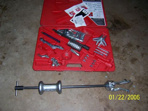 1987 Ford Bronco - A red toolbox contains a slide hammer puller set with various attachments and instructions. A separate slide hammer is laid out in front.
