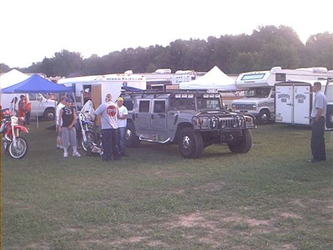 1986 Ford Bronco - A group of people stand around motorcycles and a large Hummer H1 at an outdoor event.