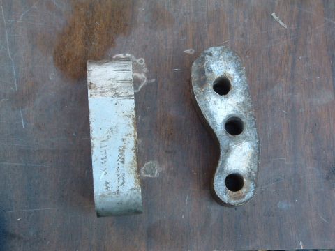 1994 Jeep YJ - Two metal bracket components are shown on a wooden surface, one piece has three holes.