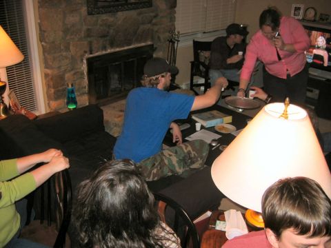 1985 Ford LTD Crown Victoria - A group of people are socializing in a living room, with a fireplace and a television visible.