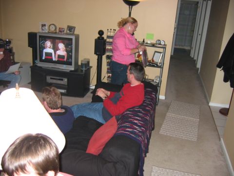 1985 Ford LTD Crown Victoria - A group of people are gathered in a living room, watching television and relaxing.