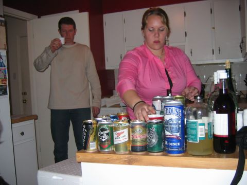 1985 Ford LTD Crown Victoria - A gathering of people around a table filled with various beer cans and bottles, suggesting a social event.