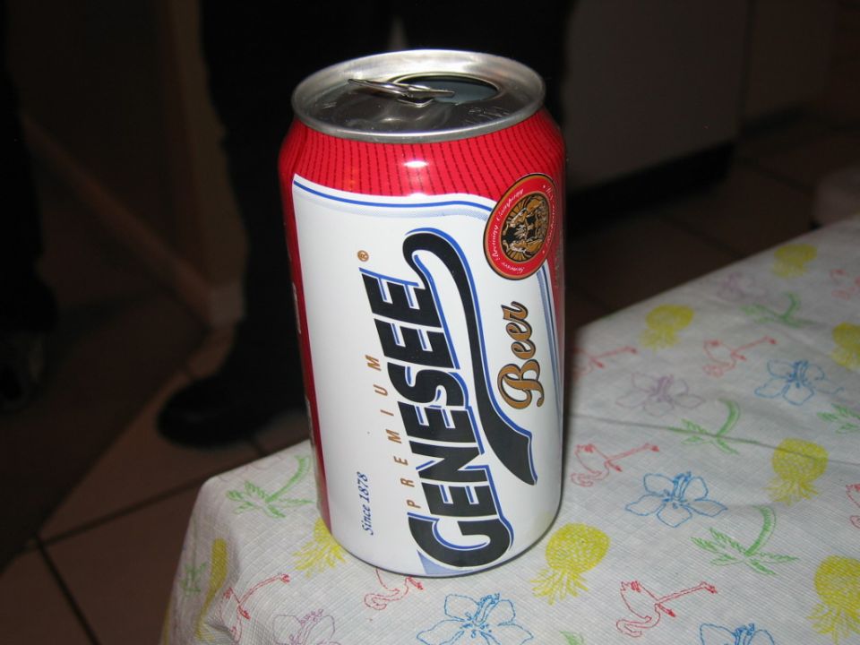 Red and white Genesee beer can tilted on a table with a floral pattern