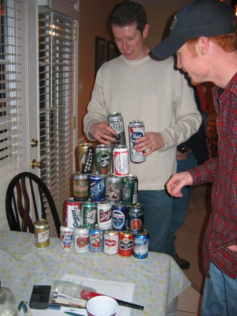 1985 Ford LTD Crown Victoria - Two men stand over a pyramid of beer cans, with one man holding two cans and the other looking on.