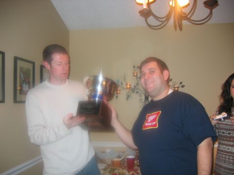 1985 Ford LTD Crown Victoria - Two men celebrate with a trophy during an indoor gathering, possibly a party or award ceremony.