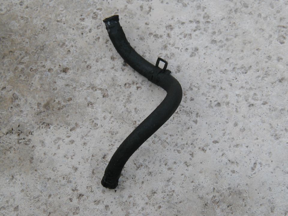 Black curved rubber hose with molded clip lying on concrete
