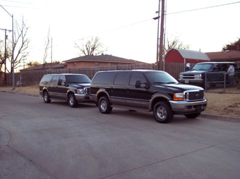 2000 Ford Excursion - Two Ford Excursions are parked on a residential street, with a third vehicle in the background.