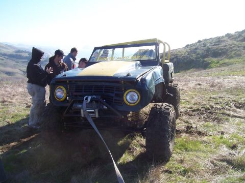 1998 Ford Ranger - Modified off-road vehicle with winch and roll cage on a grassy hillside.