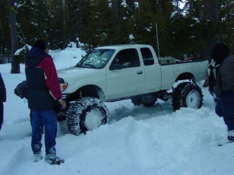 1986 Ford Bronco - Pickup truck with large tires in snow, possibly off-roading.