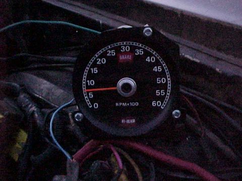 1973 Ford Ranchero - Close-up of a black-faced tachometer reading RPM x100 from 0 to 60, with a red needle near the low end and 'BRAKE' and 'HI-BEAM' indicator…