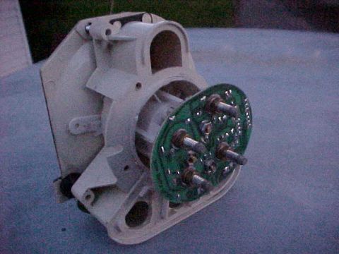 1973 Ford Ranchero - Close-up of a white plastic-housed electric motor or blower assembly with an exposed green circular circuit board, mounted with several met…