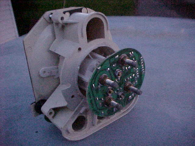 White motor housing with exposed green circuit board and metal posts