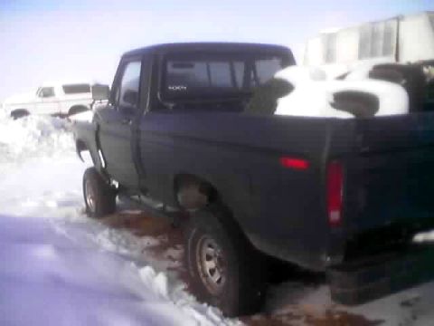 1979 Ford Bronco - A dark Ford F-Series pickup truck is parked in the snow, with a white SUV visible behind it.