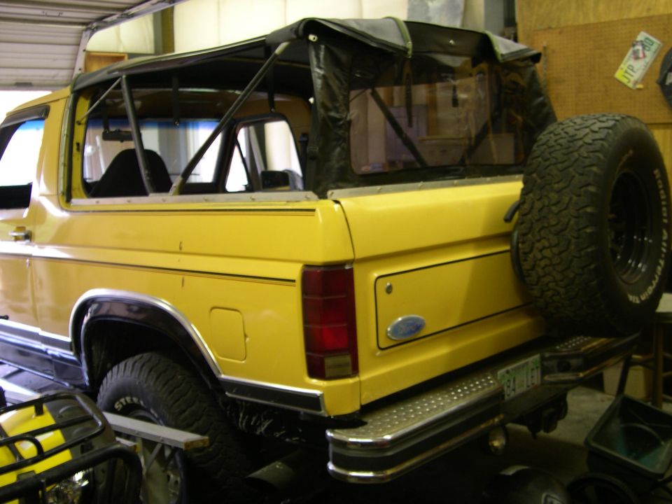 Yellow 1982 Ford Bronco rear view with soft top and spare tire