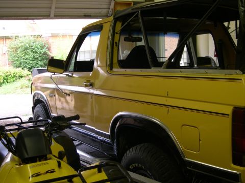 1982 Ford Bronco - Yellow Ford Bronco parked inside a garage, with an ATV partially visible in the foreground.