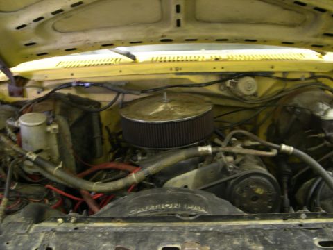 1982 Ford Bronco - The engine compartment of a vehicle is shown, various hoses, the air filter, and a fan with a caution label.