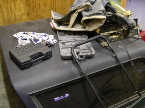 1982 Ford Bronco - A car hood and window are visible, covered with various items including tool cases and a cloth.