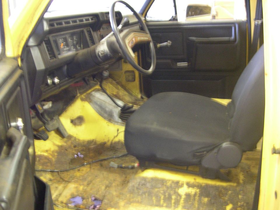 Stripped truck interior with bare yellow floor pan and gray bucket seat