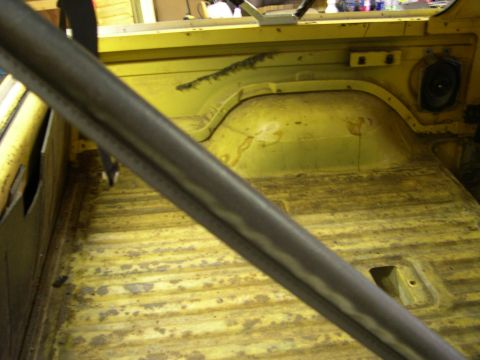 1982 Ford Bronco - The interior of a yellow vehicle shows a worn floor and a prominent roll bar, suggesting it may be undergoing restoration.