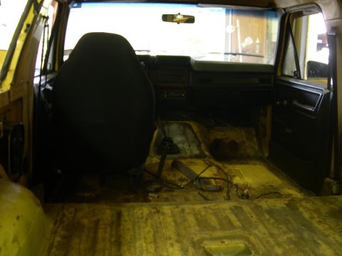 1982 Ford Bronco - Interior view of a yellow vehicle, likely from the early 1980s, with a worn floor and dashboard.